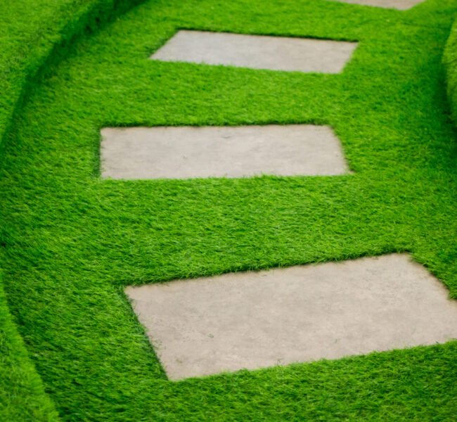 Artificial green grass walk way with concrete plate background